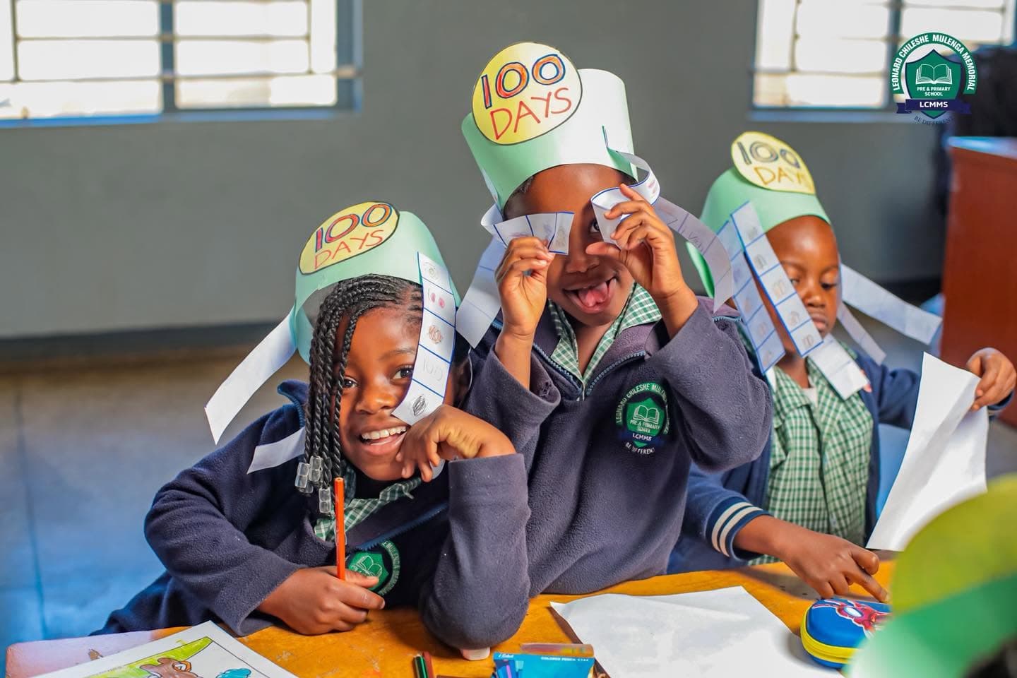 Learners in 100 Days crowns share a cheerful moment at their classroom table