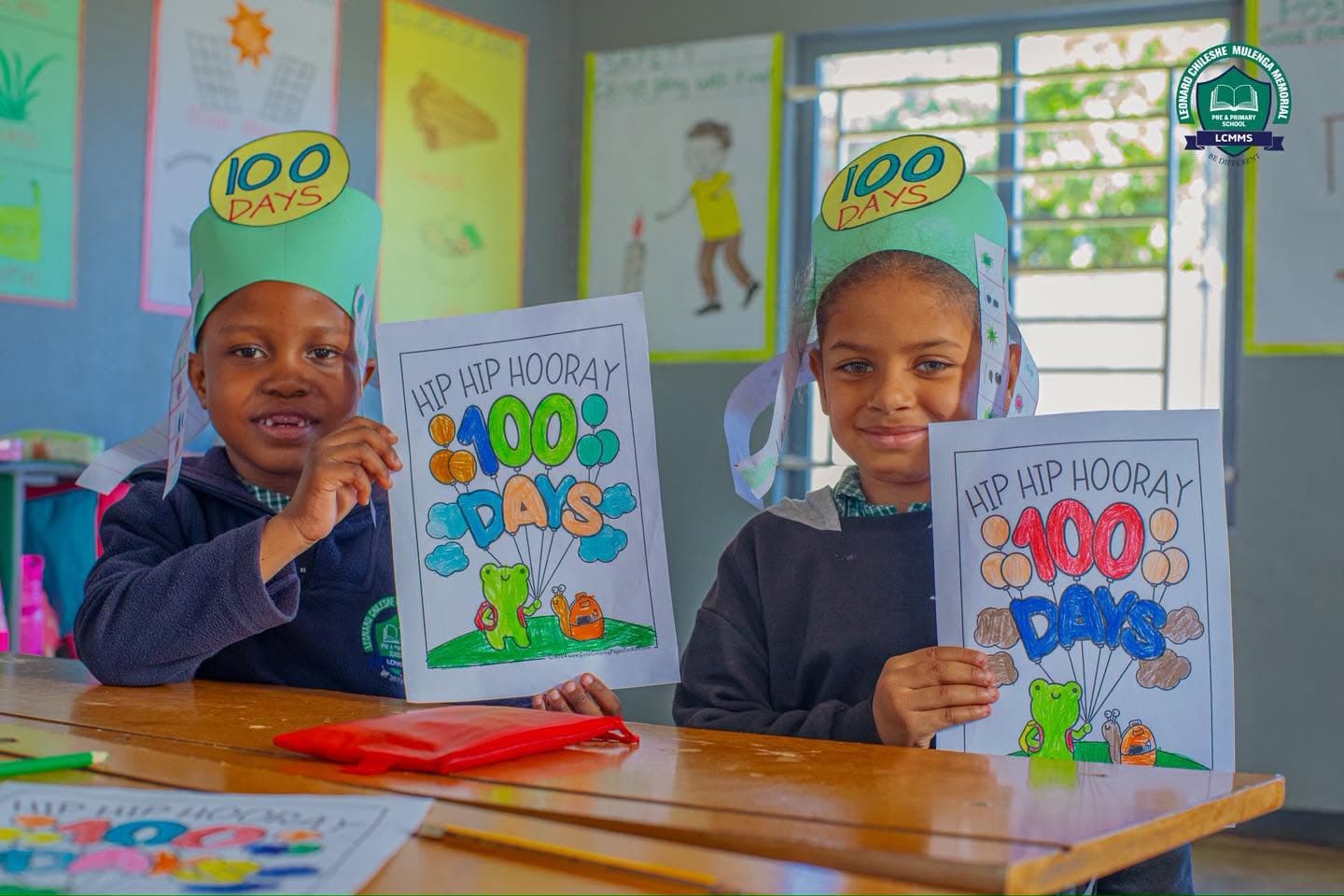 Two learners proudly show their completed 100 Days colouring sheets