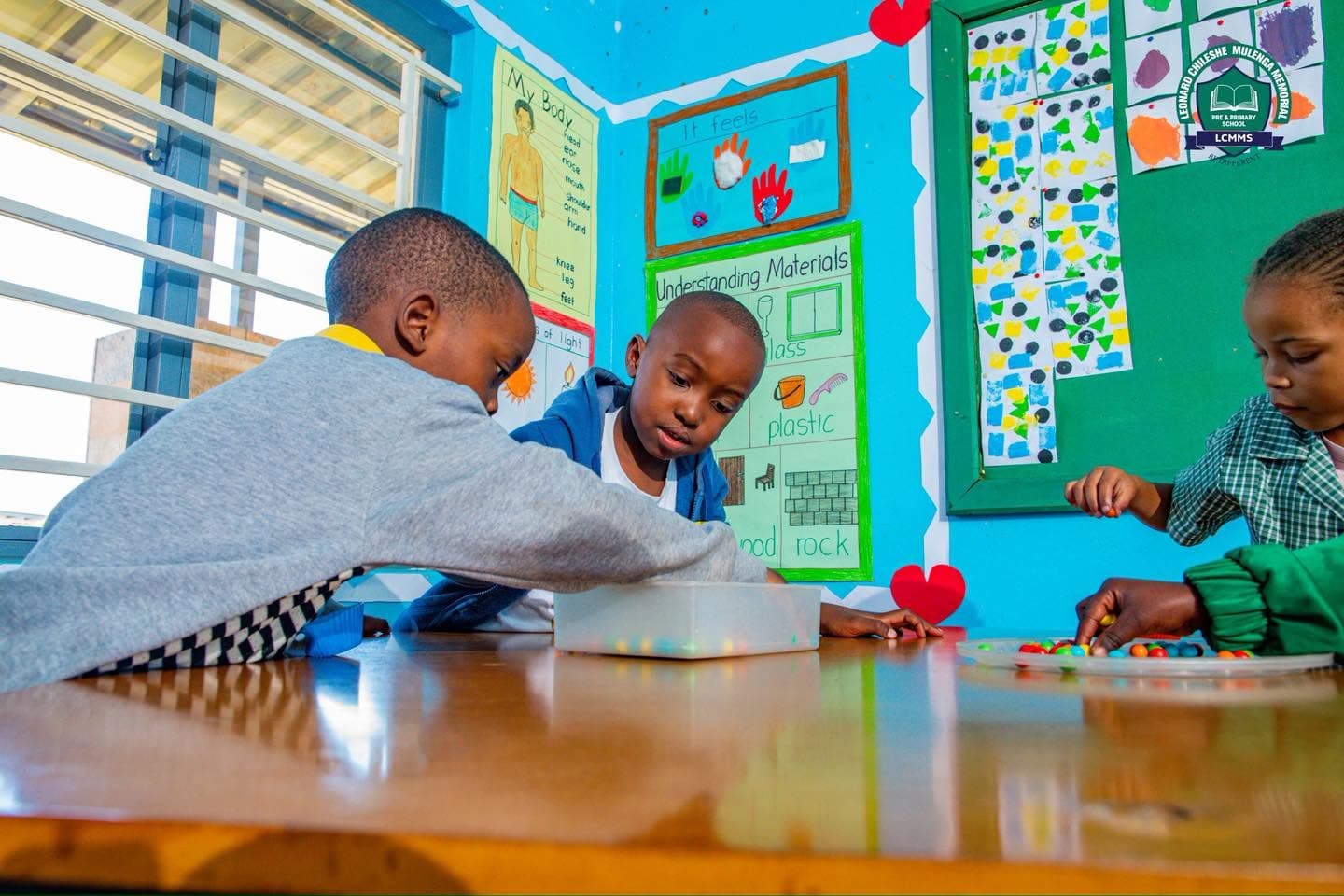 Children work together with colourful materials at a classroom table