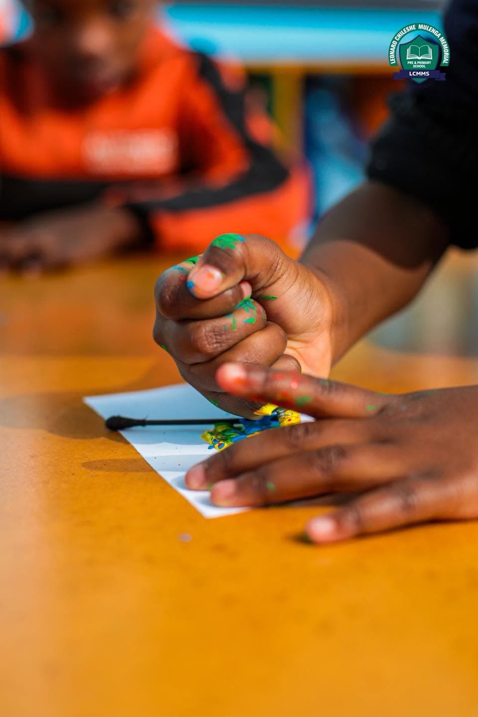 A close view of a child's hands making colourful artwork on paper