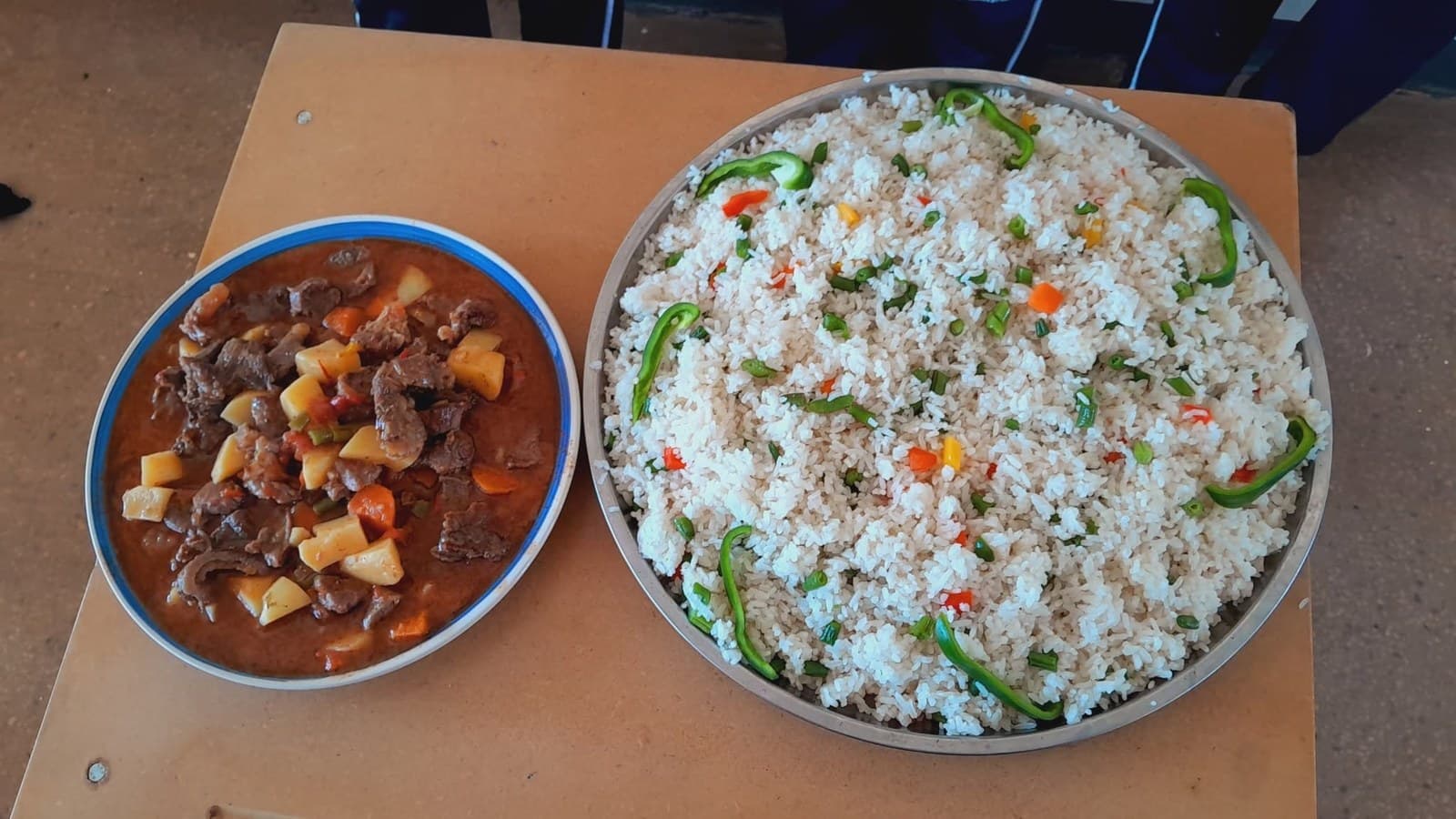 A bowl of rice with vegetables beside a serving of stew prepared during the cooking activity