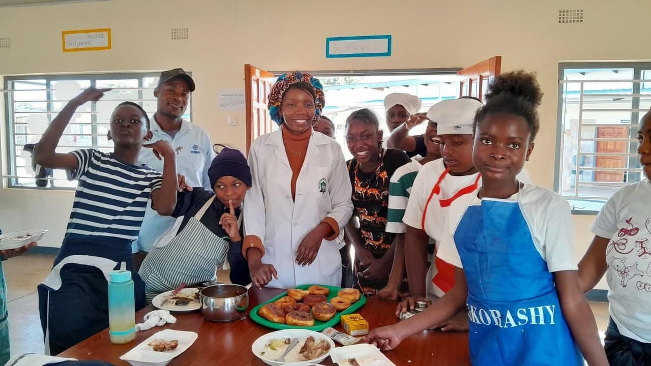 Grade 7 learners celebrate together behind a table of prepared food