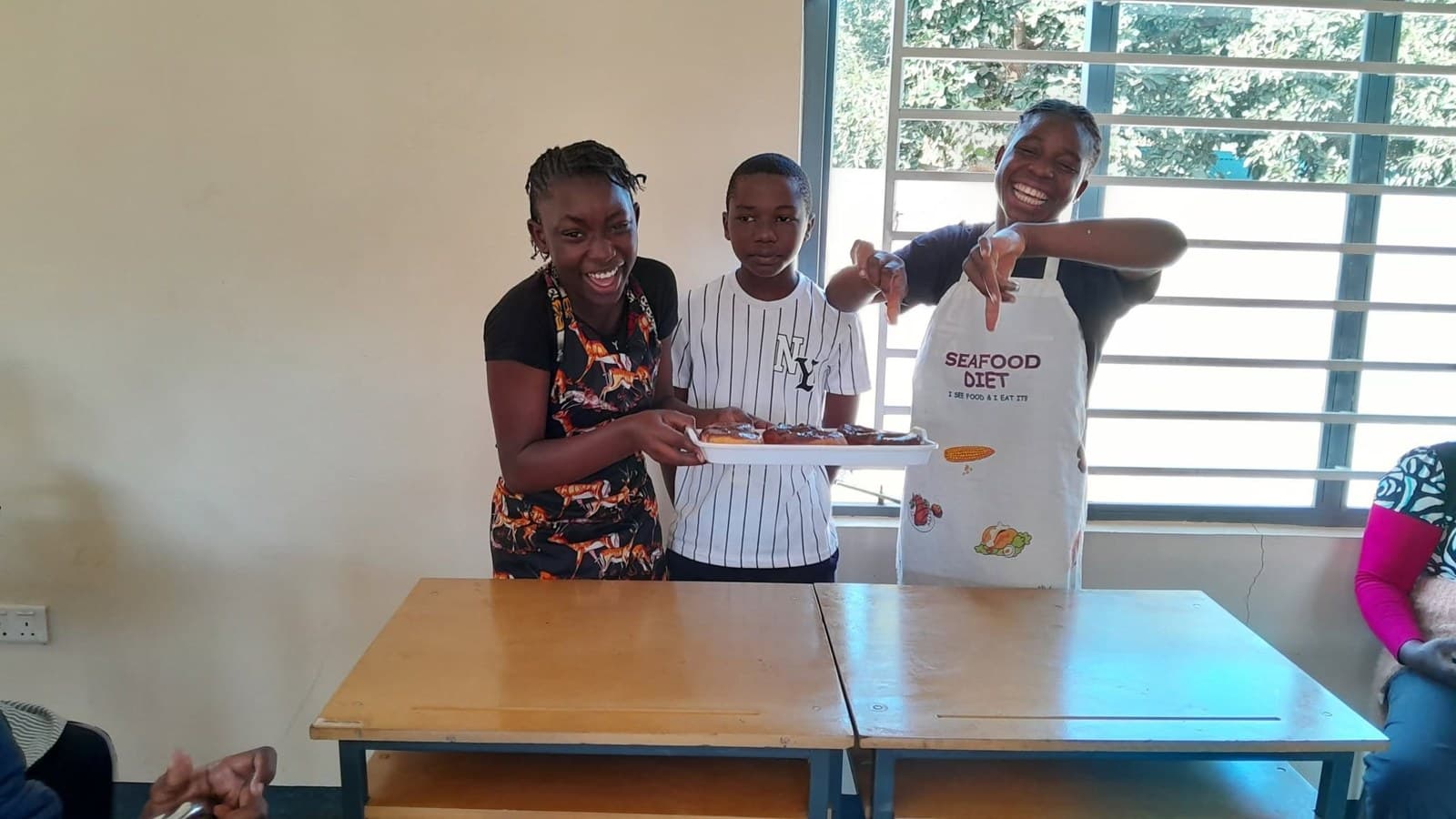 Three Grade 7 learners stand together behind their cooking presentation table