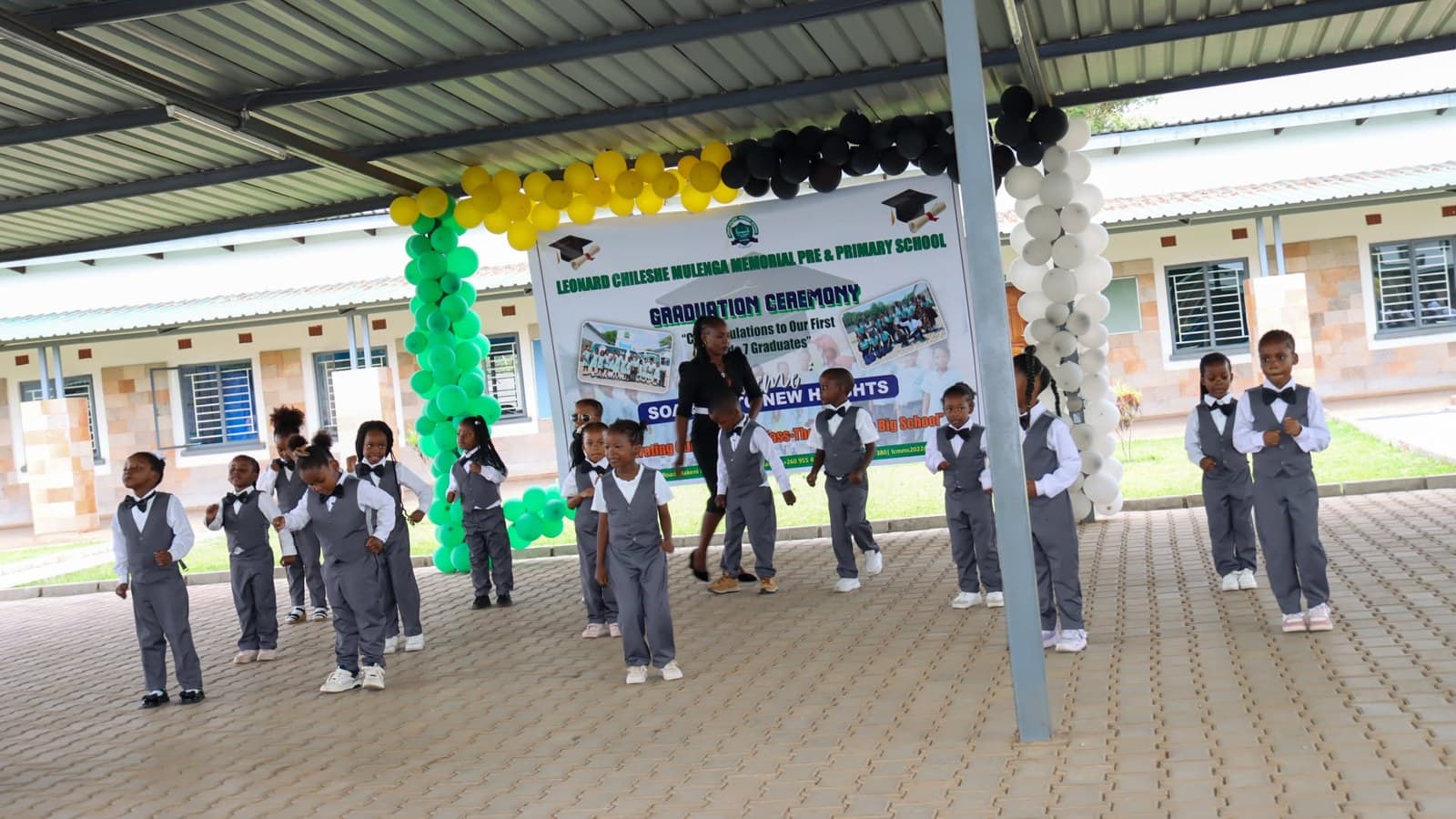 Learners in school uniform stand in formation beneath the graduation ceremony decorations