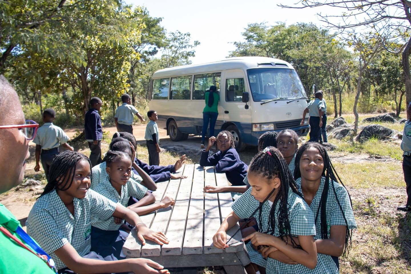 Learners share a meal at picnic tables near the school transport during the park visit