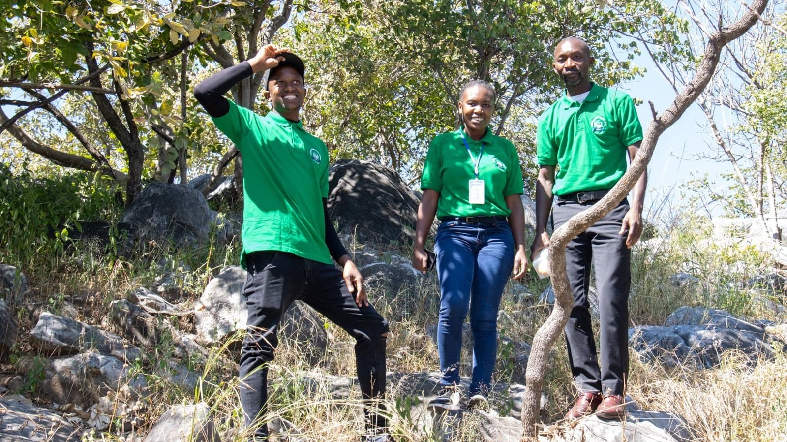Three staff members pause for a photograph among the trees
