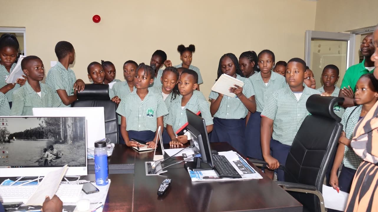 The school group gathers beside desks and equipment during the newspaper office tour