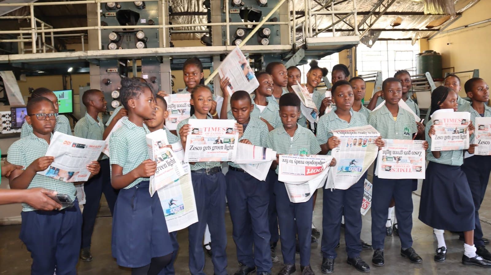 Learners and staff pose with newspaper copies in the production area