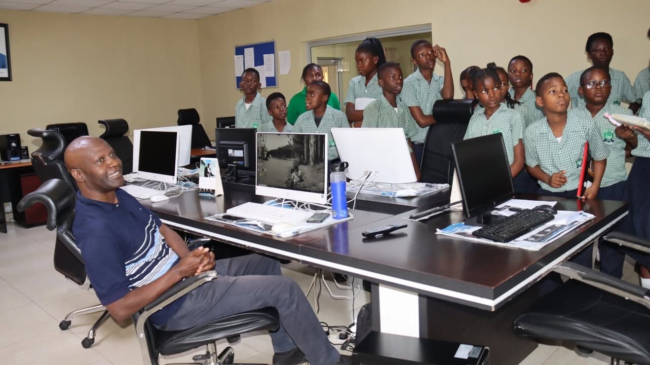 Learners gather around a seated newspaper staff member during the office visit
