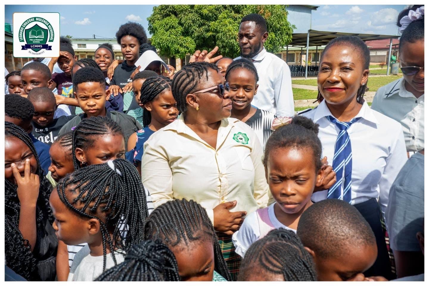 Teachers in school uniform among a crowd of smiling pupils