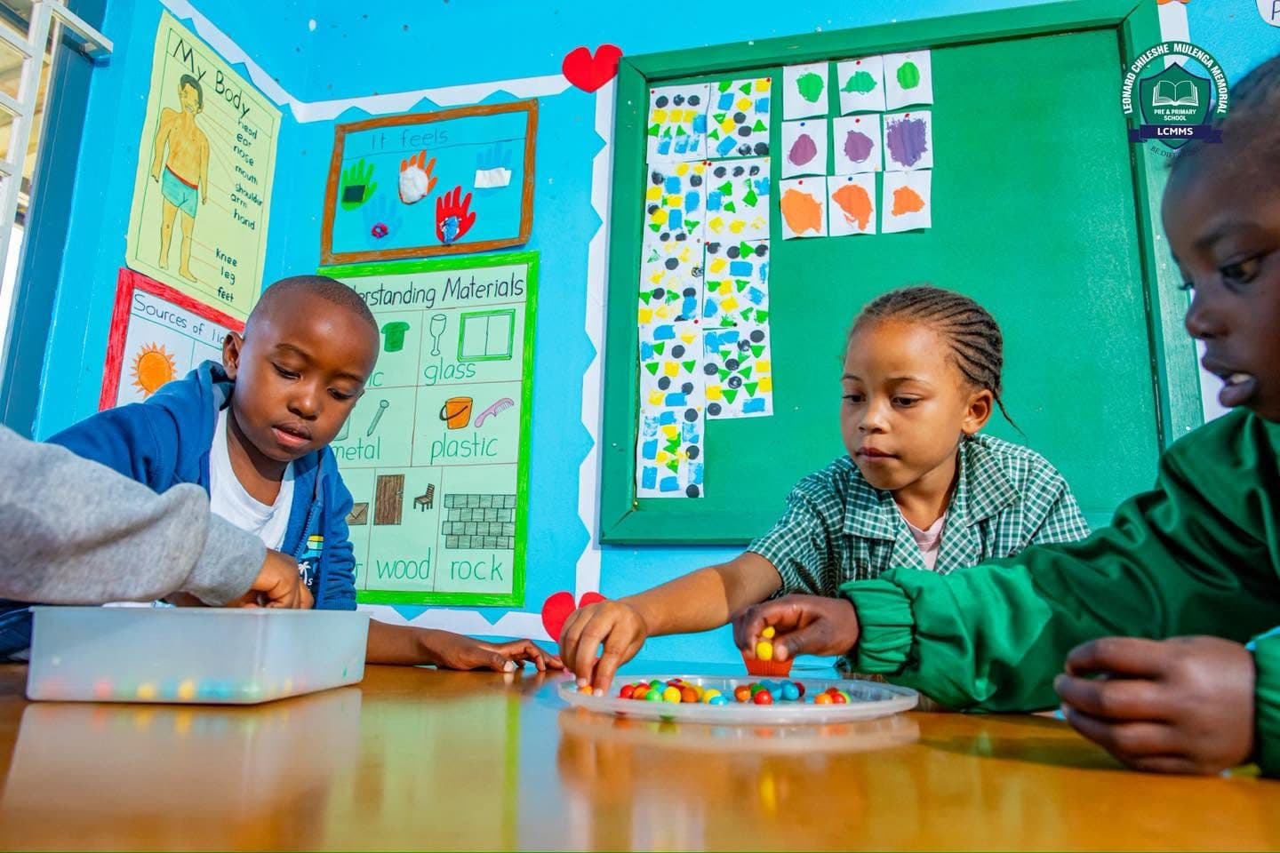 Young pupils sorting coloured beads at a classroom table