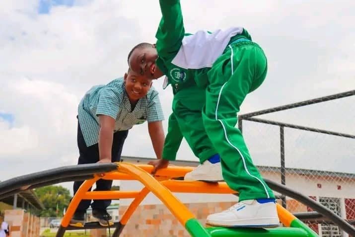 Two pupils climbing the orange and green climbing frame on the playground
