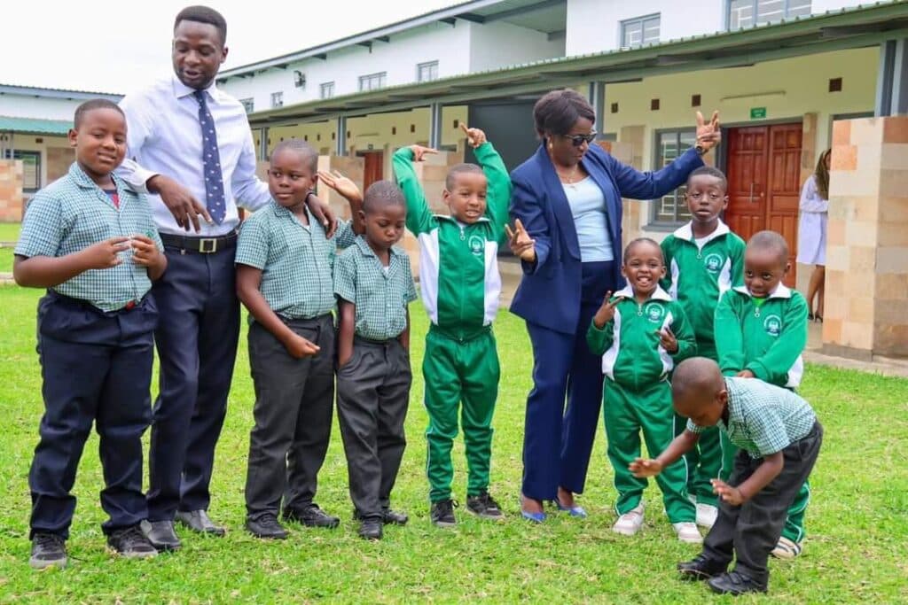 Pupils in green school uniforms with their teachers outside the classrooms