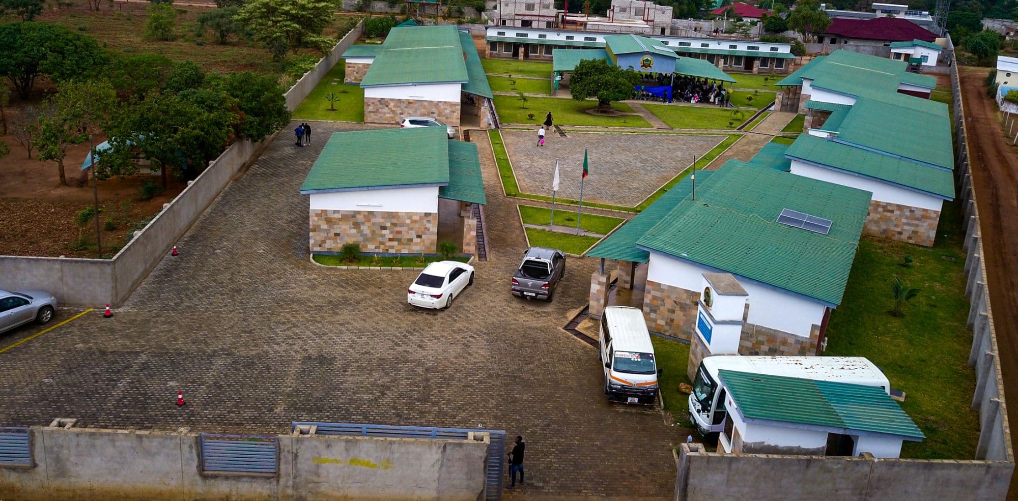 Aerial view of the school entrance, car park and flag poles in front of the classroom blocks