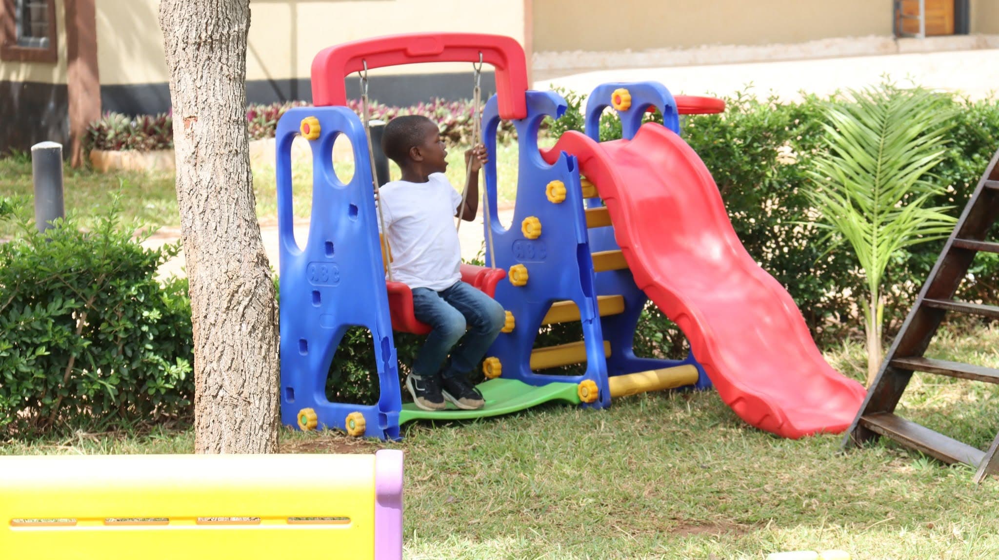A learner sitting on a playground swing beside a slide