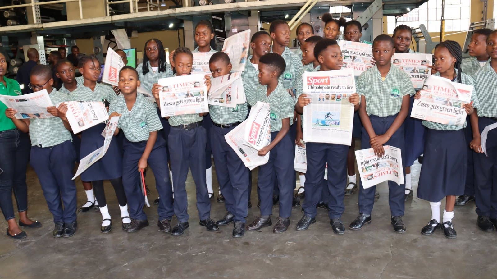 Learners hold copies of the newspaper in the printing production area